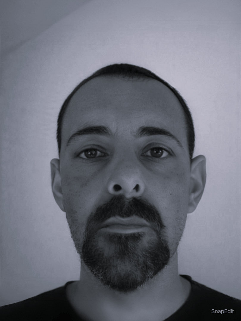 Equipo 1 Retrato frontal de un hombre con barba y expresión seria, sobre fondo claro y neutro